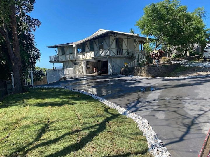 A large house is sitting on top of a hill next to a driveway.