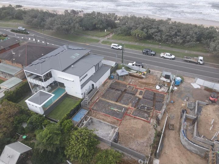 An aerial view of a house under construction next to a beach.