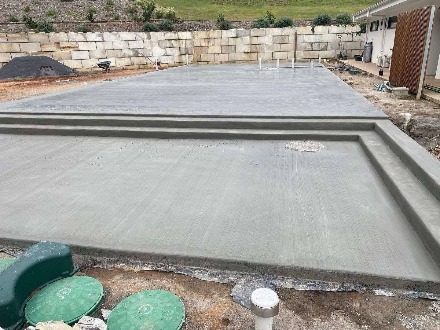 A black garage with a concrete driveway leading to it on the Sunshine Coast