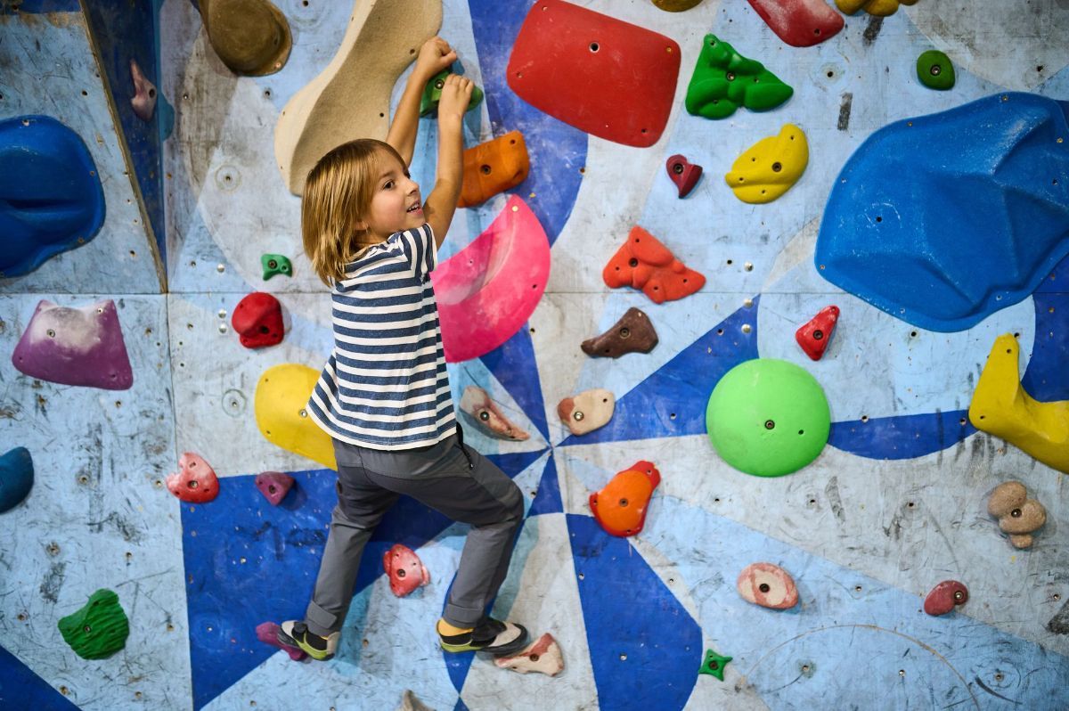 A young boy is climbing a climbing wall.