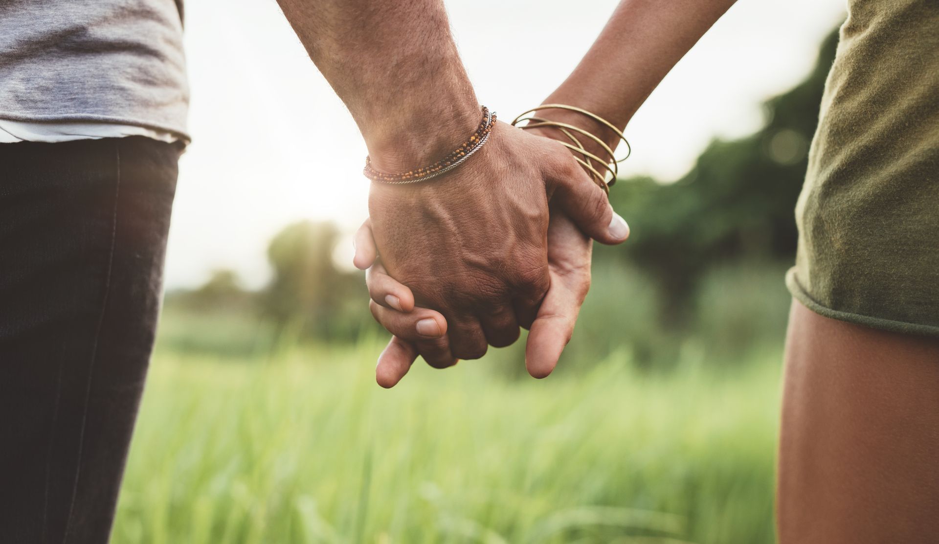 A man and a woman are holding hands in a field.