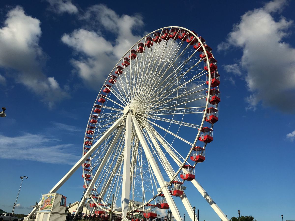 A ferris wheel is against a blue sky with clouds
