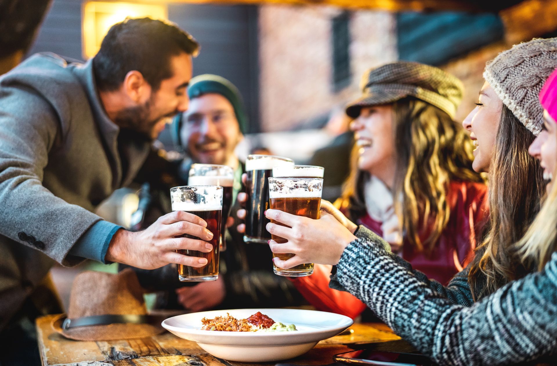 A group of people are sitting at a table toasting with beer.