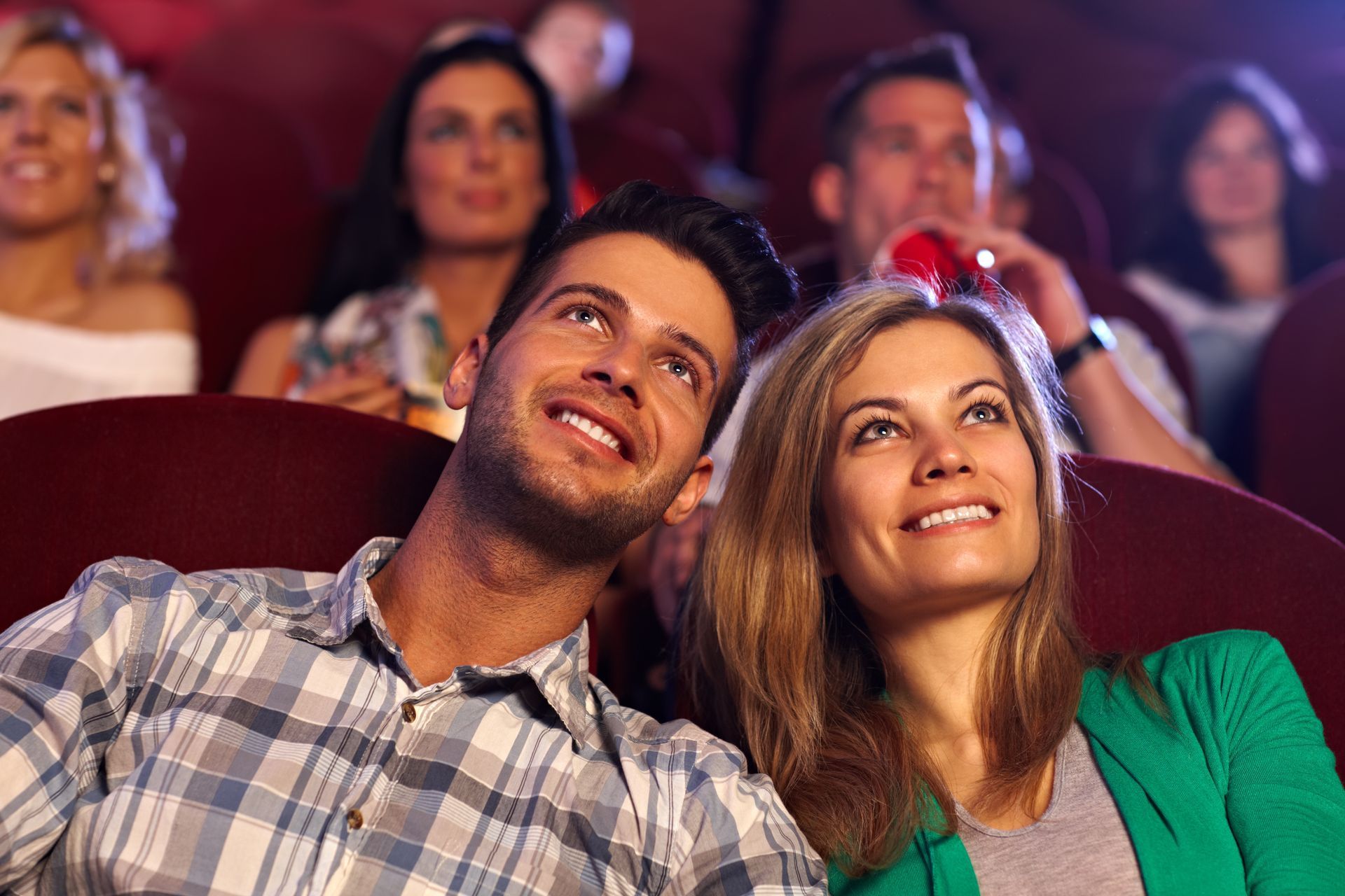 A man and a woman are sitting in a theater watching a movie.