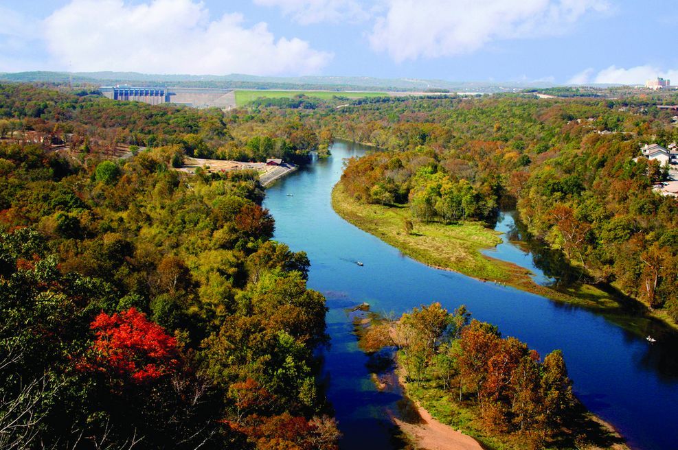 An aerial view of a river surrounded by trees on a sunny day.