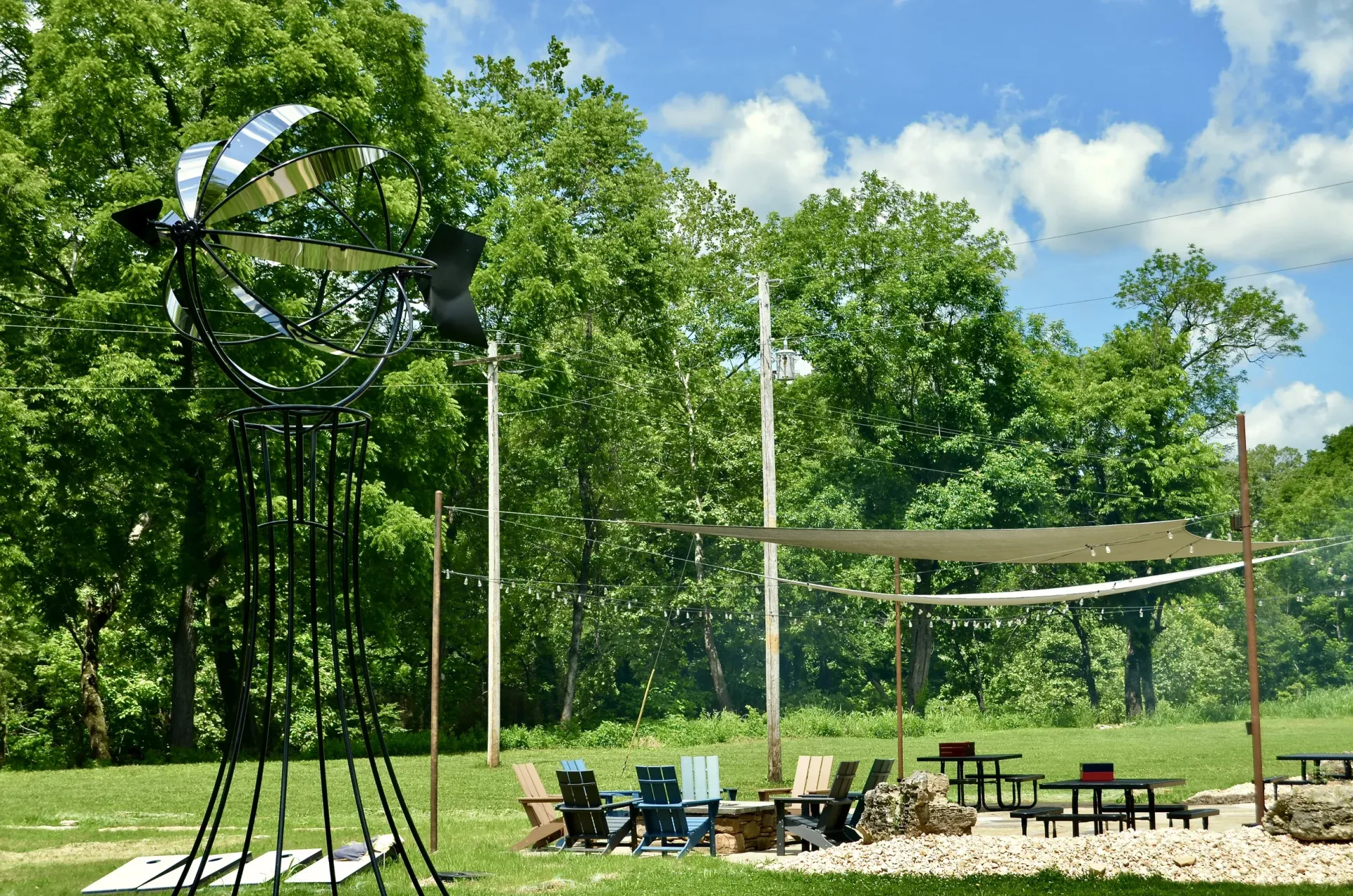 A windmill is sitting in the middle of a field next to a picnic table and chairs.