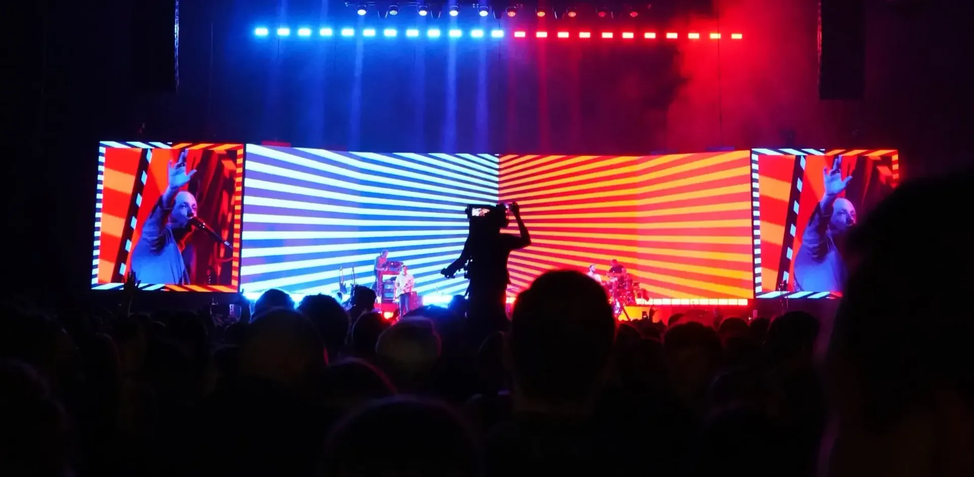 A group of people are standing in front of a stage at a concert.