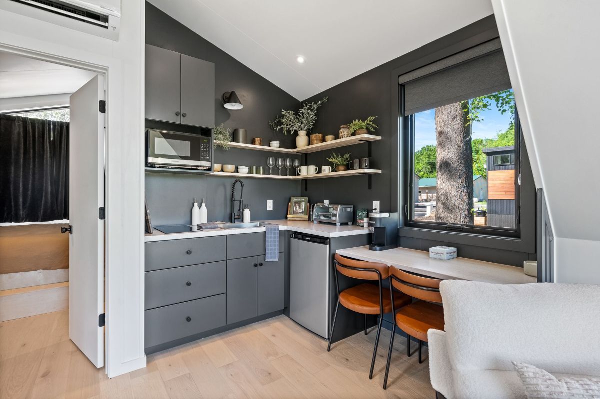 A kitchen with gray cabinets , stainless steel appliances , a table and chairs.