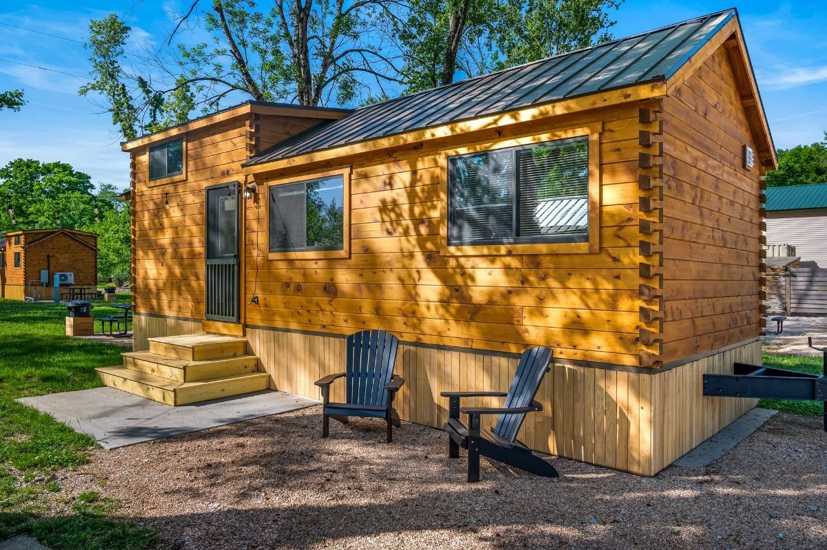 A small wooden cabin with two chairs in front of it.