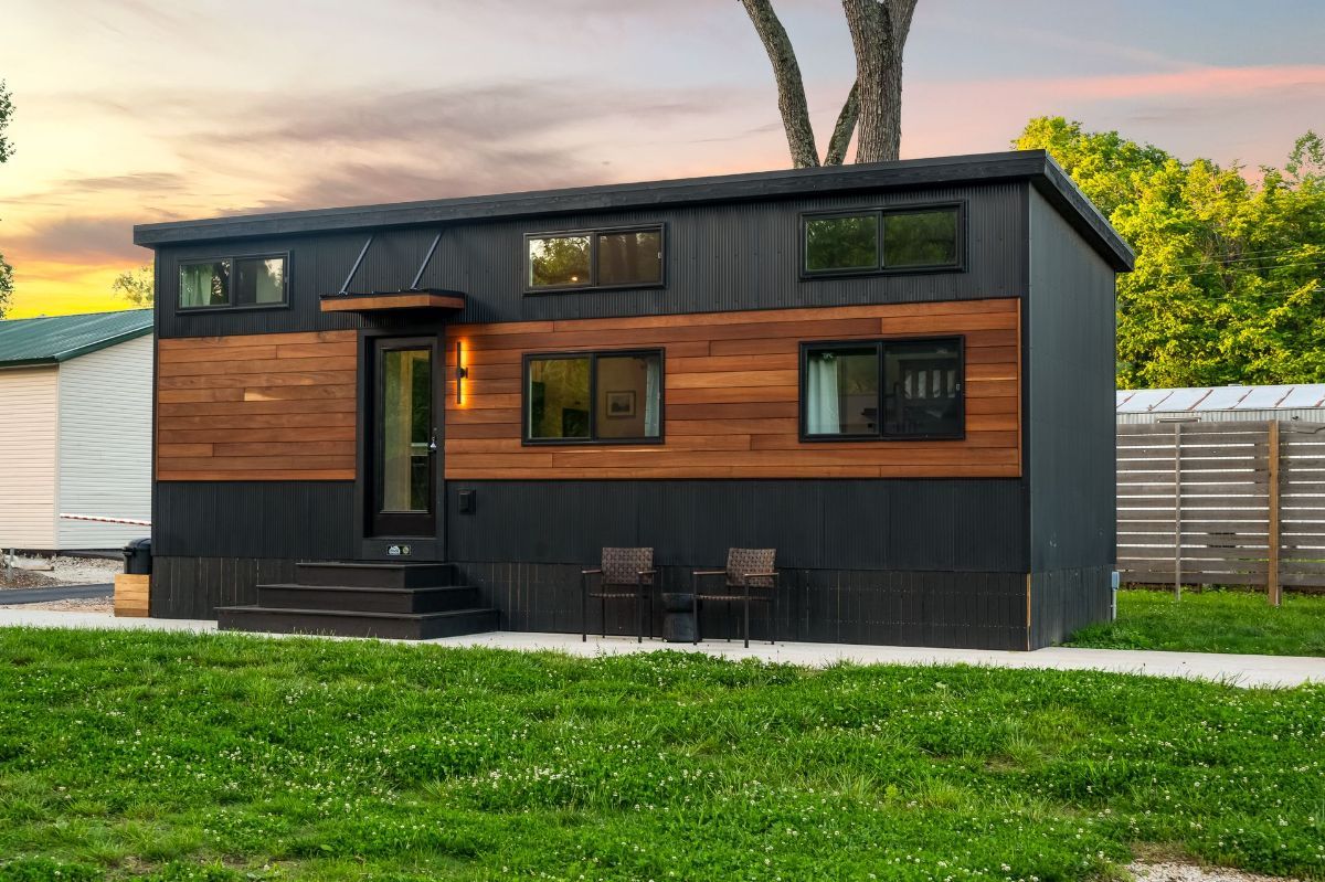 A tiny house is sitting on top of a lush green field.