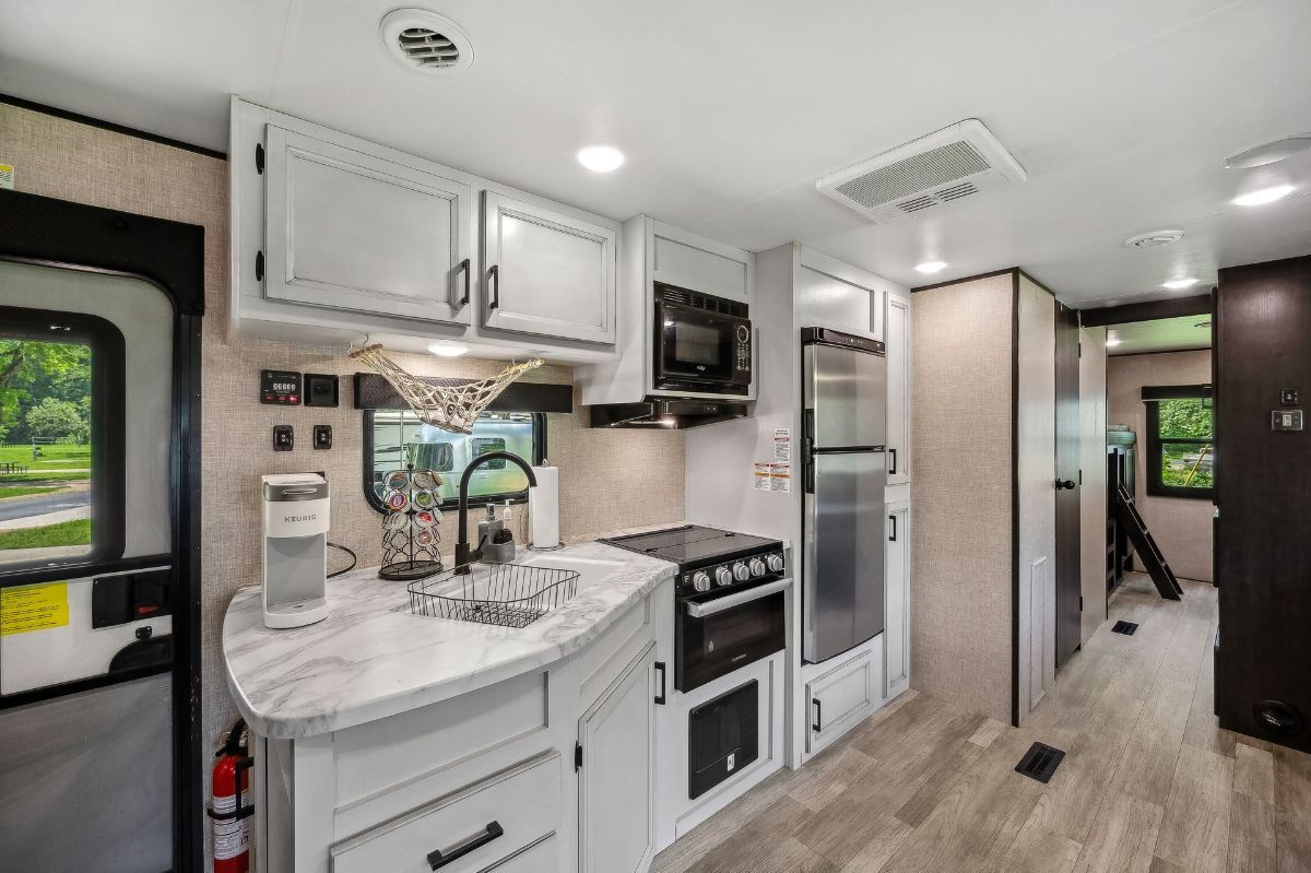 A kitchen in a rv with stainless steel appliances and white cabinets.