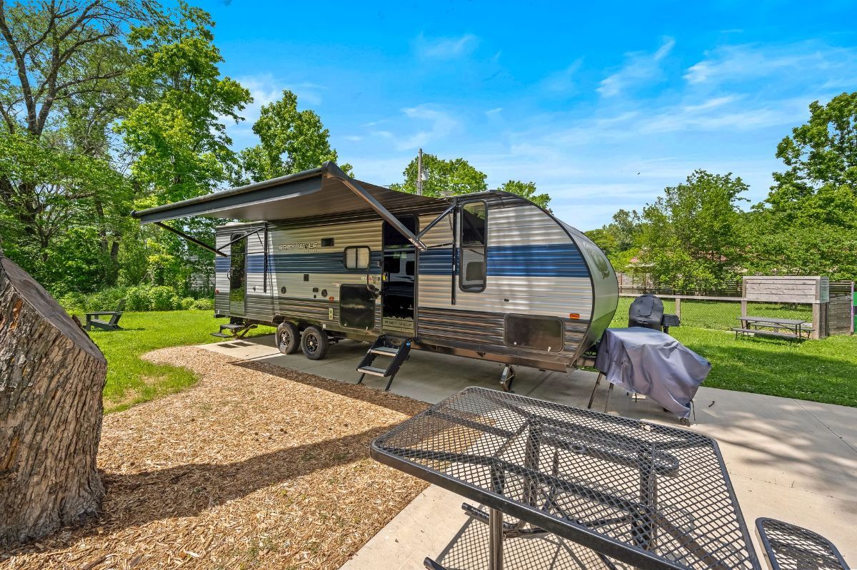 A rv is parked in a parking lot next to a picnic table and chairs.