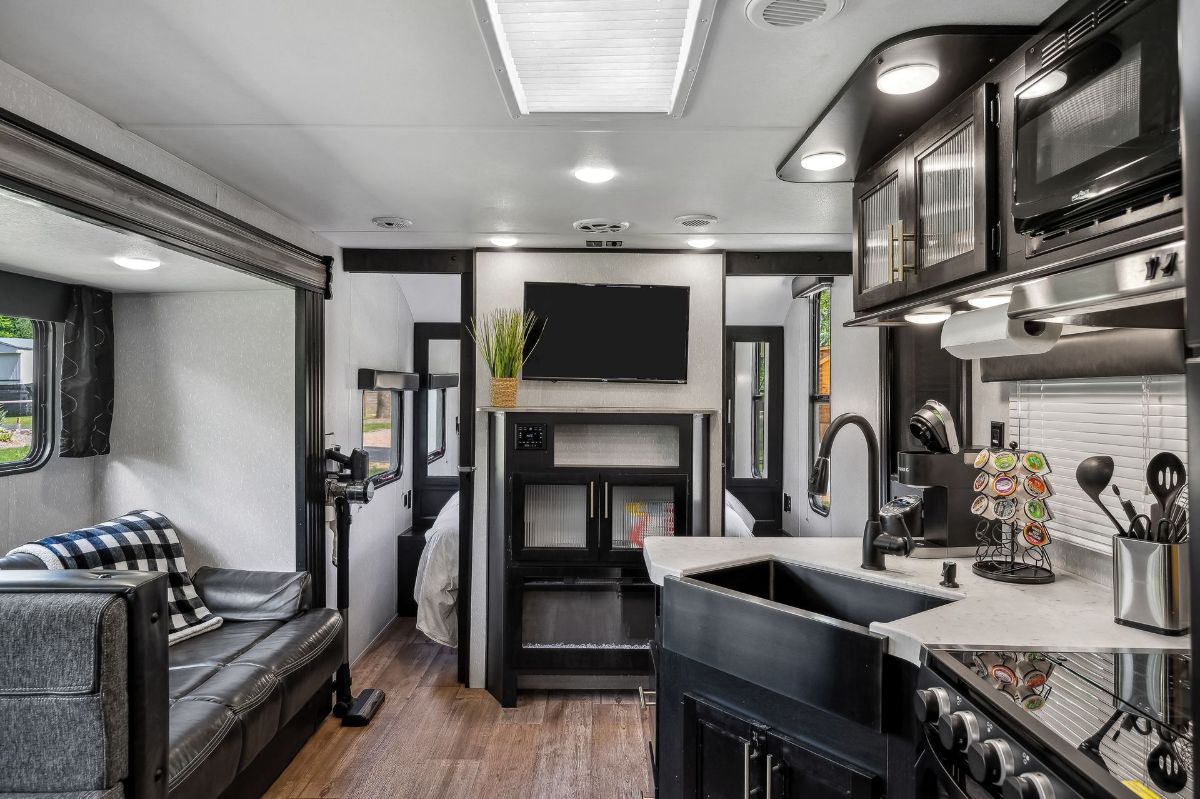 A kitchen in a rv with a sink , stove and television.