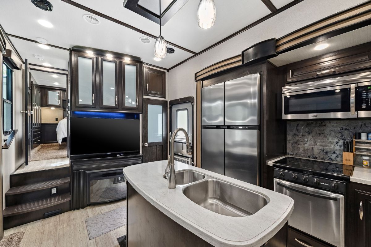 A kitchen with a sink , stove , refrigerator , microwave and television.