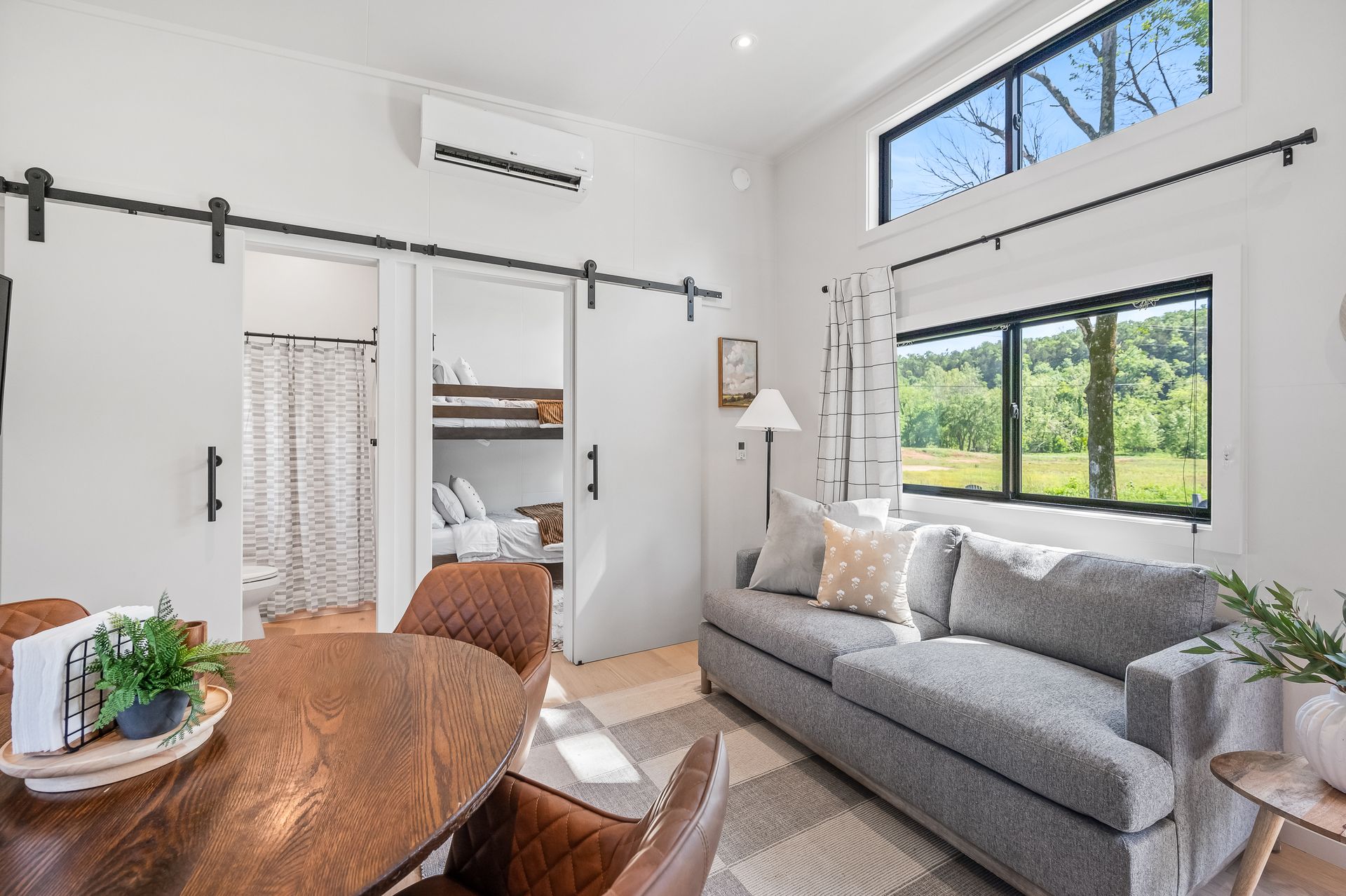 A living room with a couch , table , chairs and bunk beds.