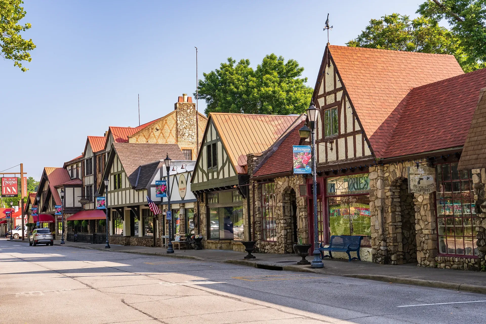 Tudor-style buildings line a street with shops and businesses; sunny day, blue sky.