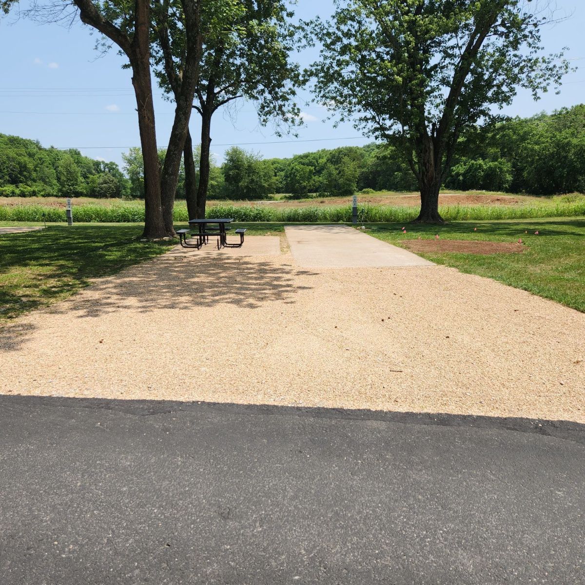 A gravel road leading to a picnic table in a park