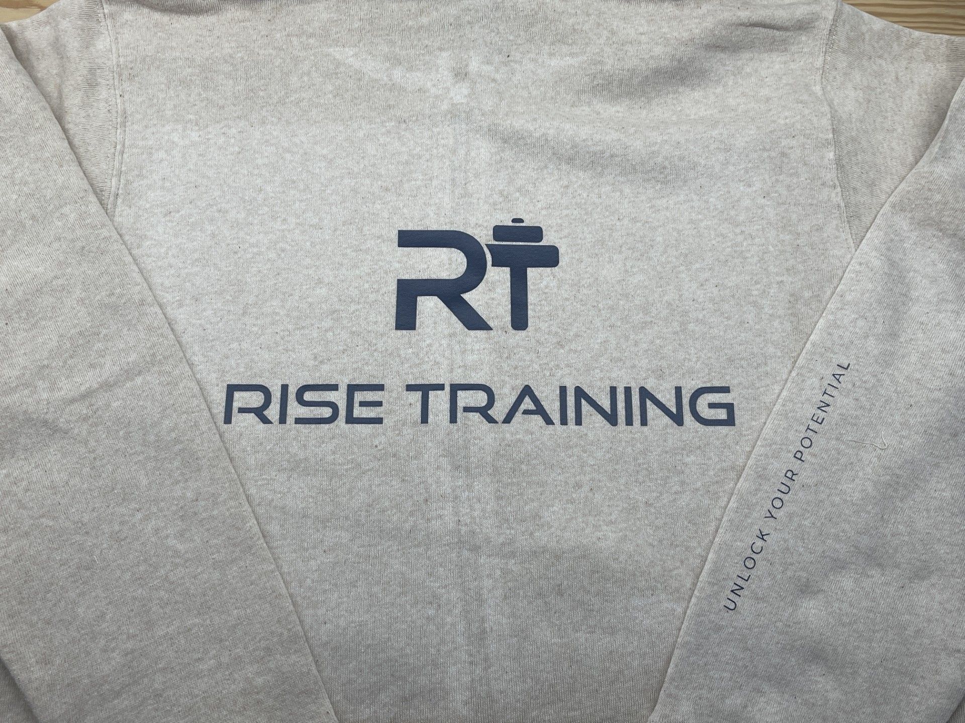 The back of a grey sweatshirt with the word rise training on it.