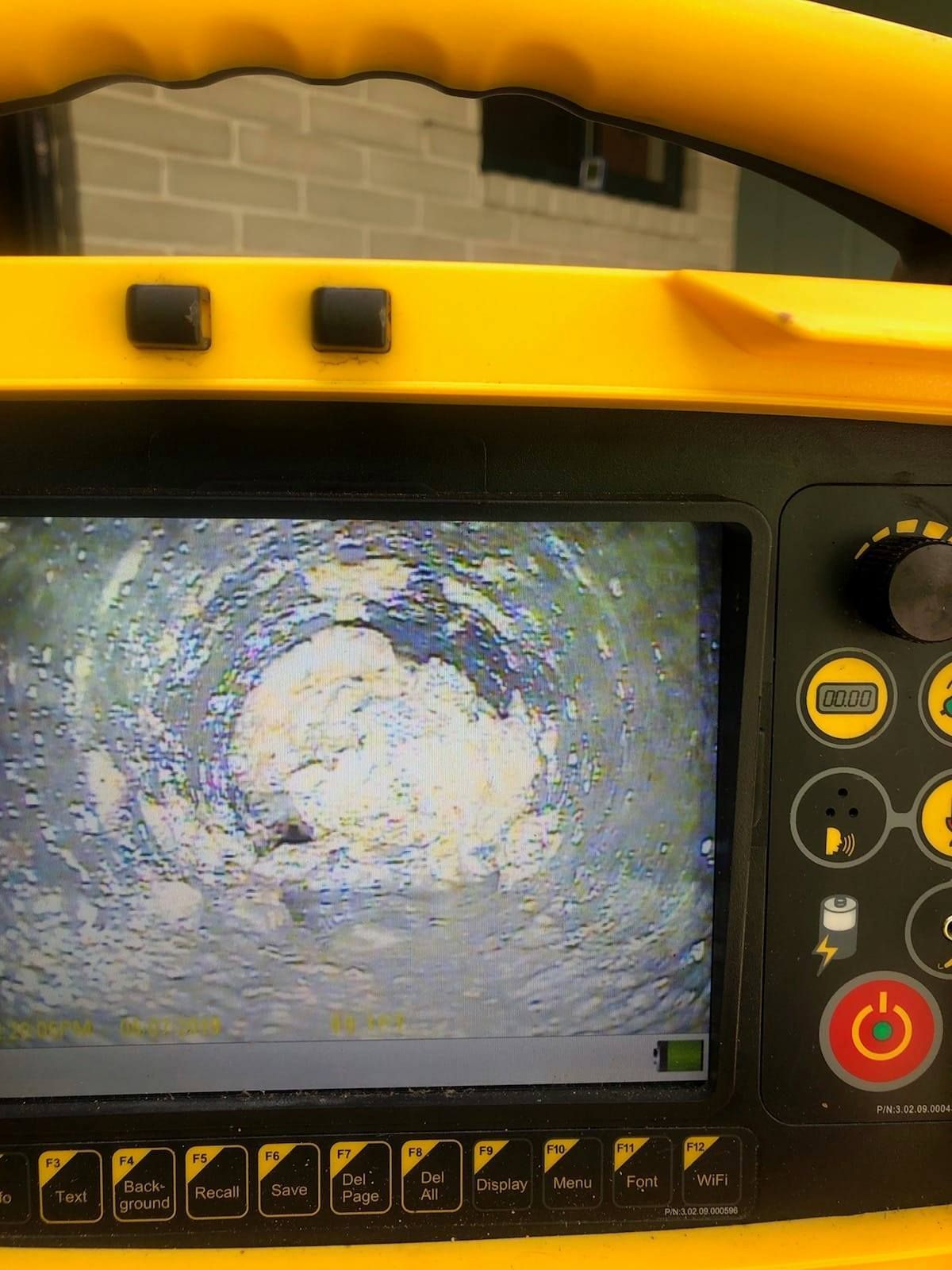Yellow inspection camera screen displaying a view inside a pipe. A large white mass blocks the view.