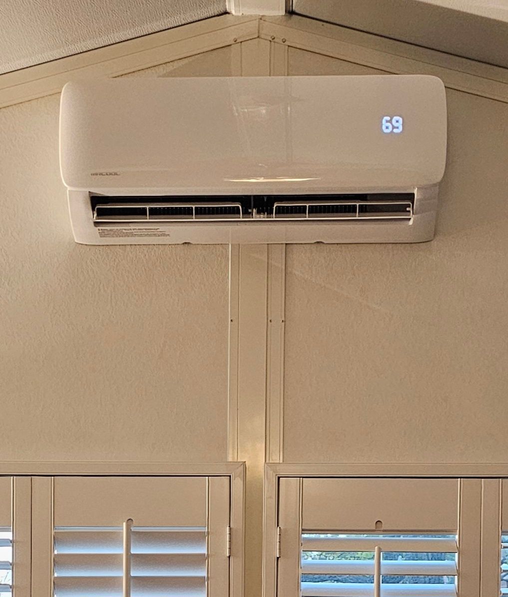 White wall-mounted air conditioner above windows, showing 69 on the display.
