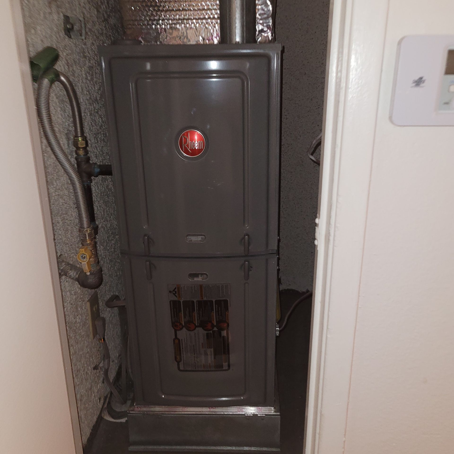 Open electrical breaker panel in a narrow wall alcove, with exposed wiring below.