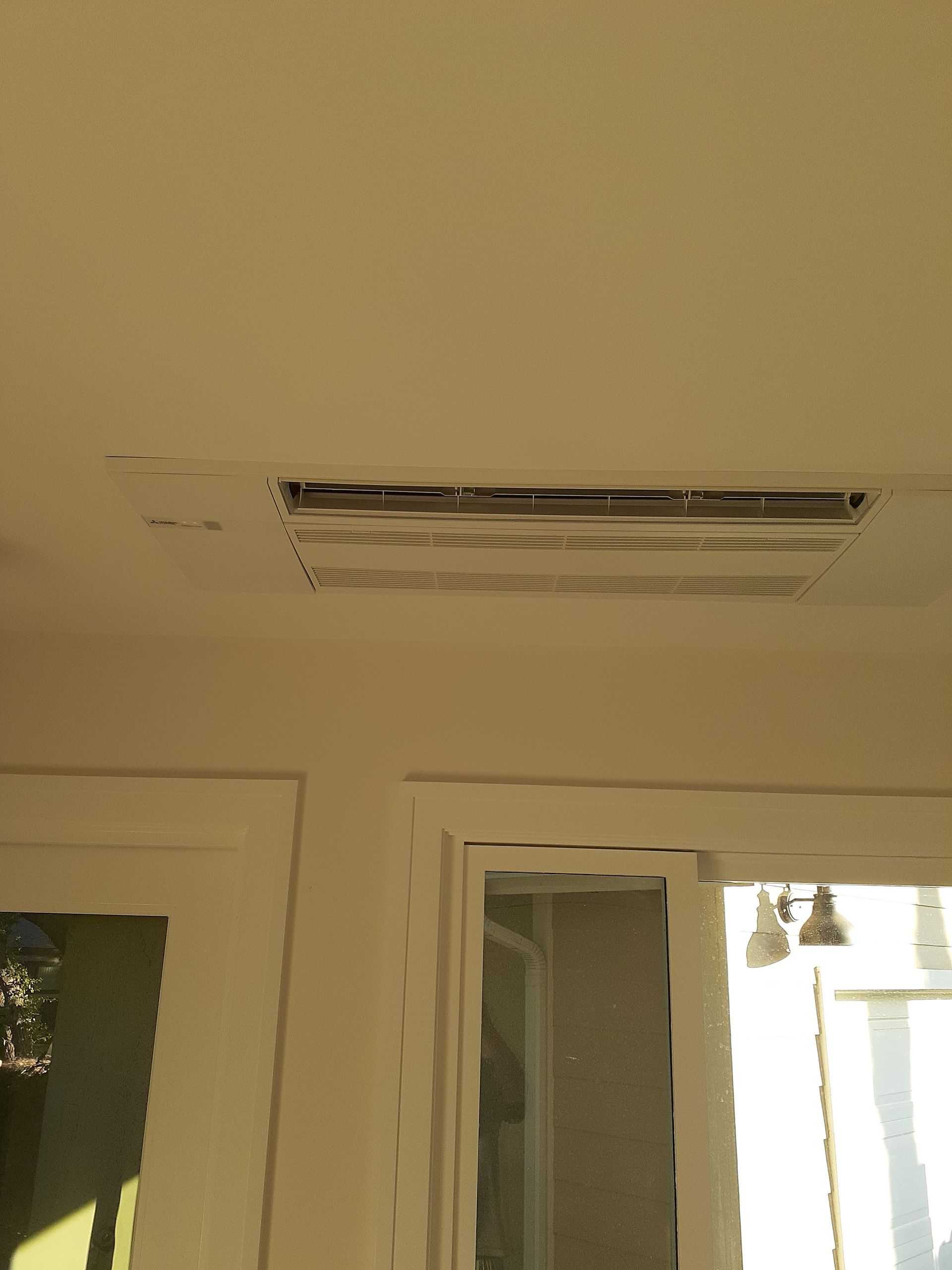 Ceiling-mounted air vent above a doorway in a beige interior room