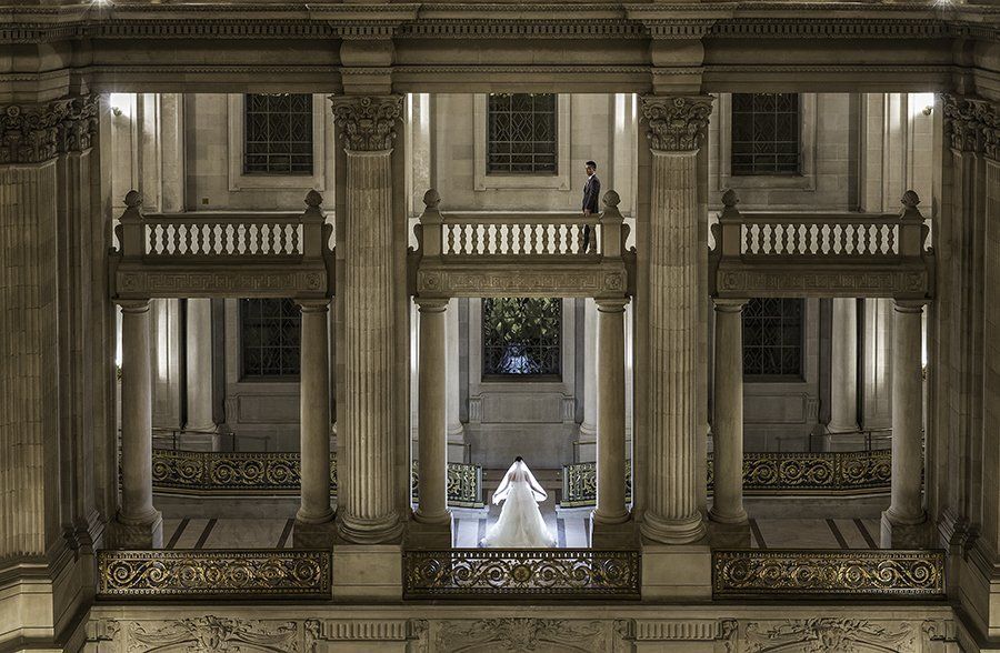 A woman in a wedding dress is standing on a balcony of a building