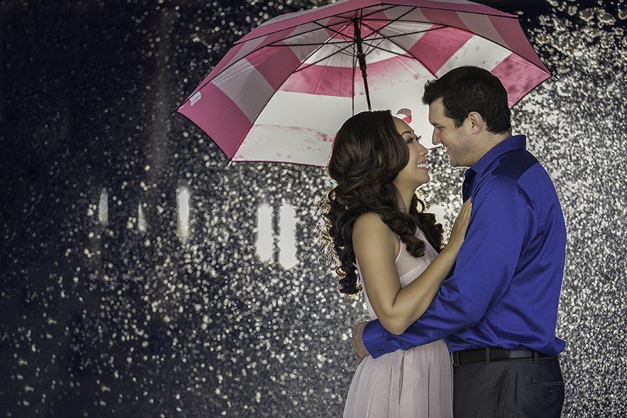 A man and a woman are kissing under an umbrella in the rain.