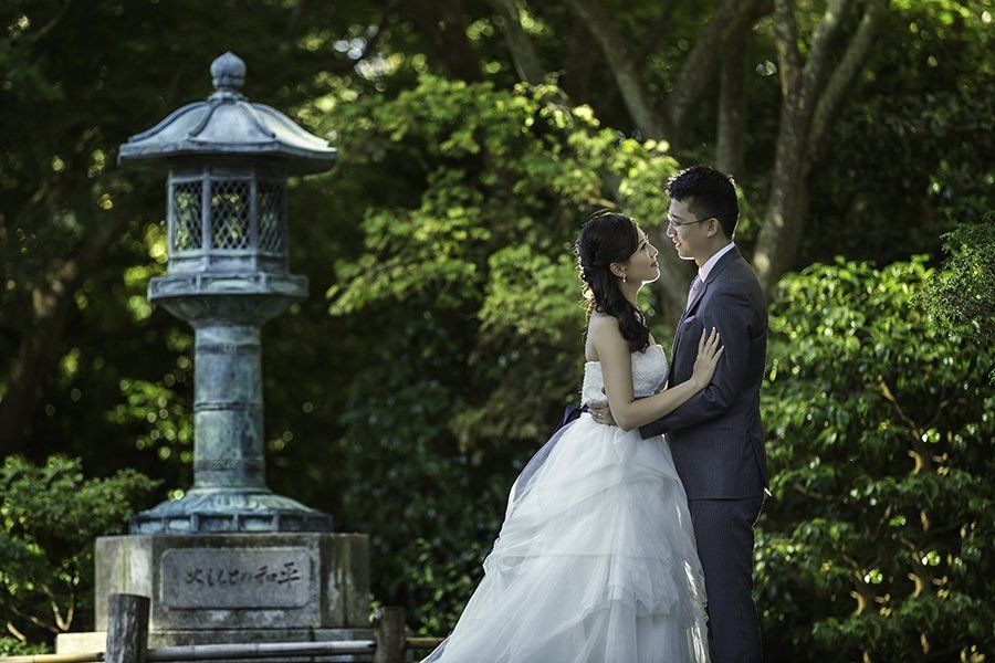 A bride and groom are posing for a picture in front of a lantern.