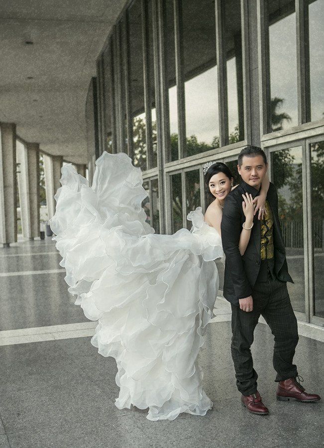 A bride and groom are posing for a picture in front of a building.