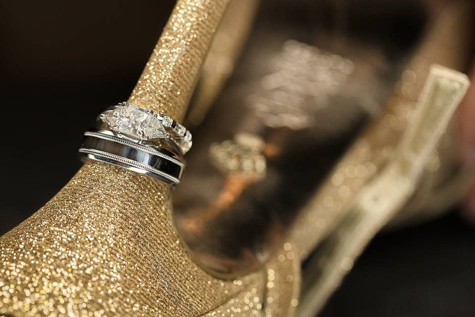 A pair of wedding rings sitting on top of a gold shoe.