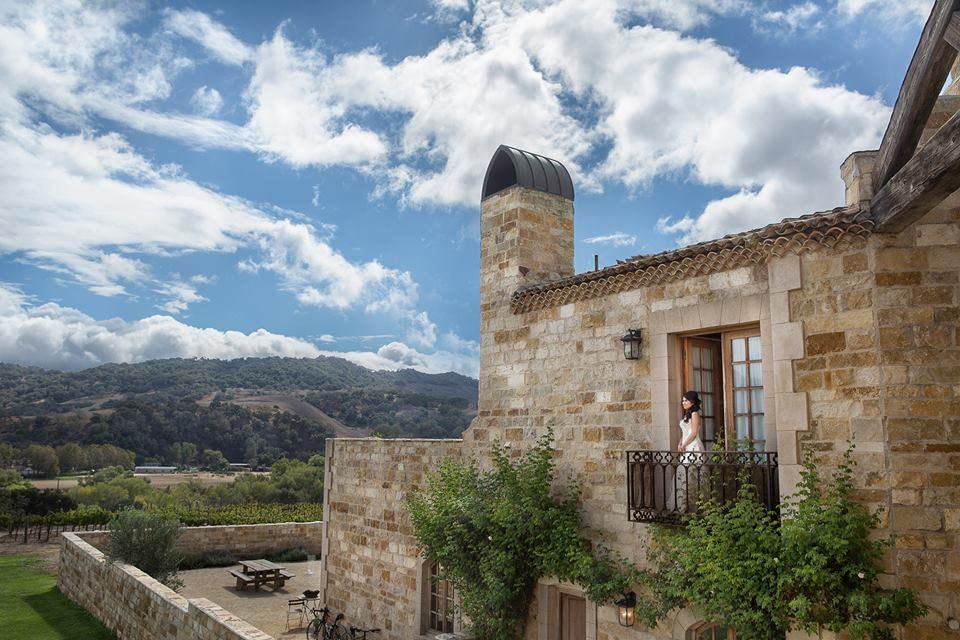 A man and woman are standing on a balcony of a stone building.