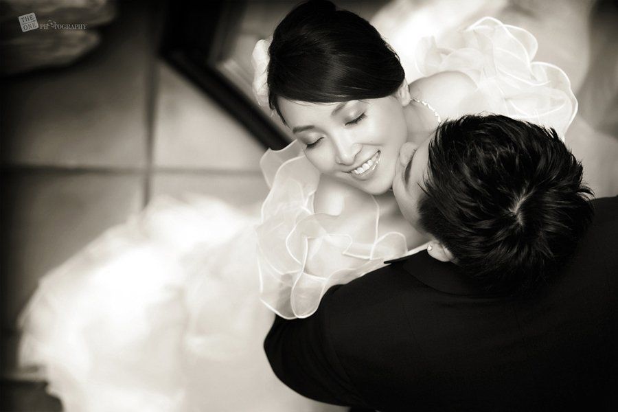 A bride and groom are kissing in a black and white photo.