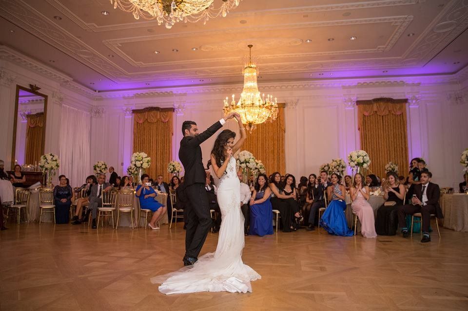 A bride and groom are dancing in a ballroom at their wedding reception.