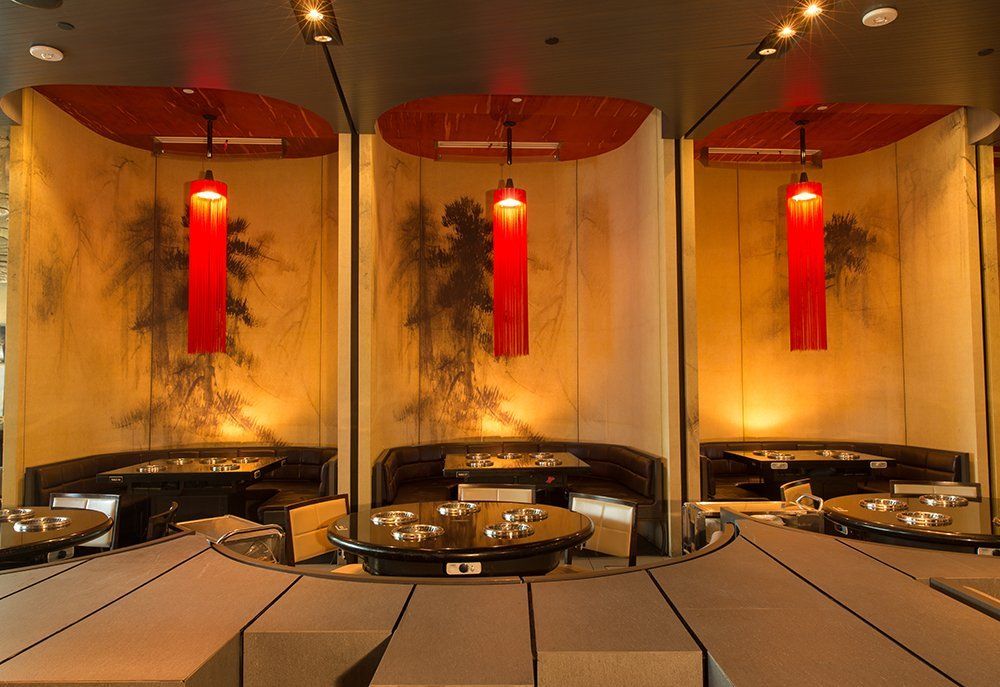 A restaurant with tables and chairs and red lanterns hanging from the ceiling