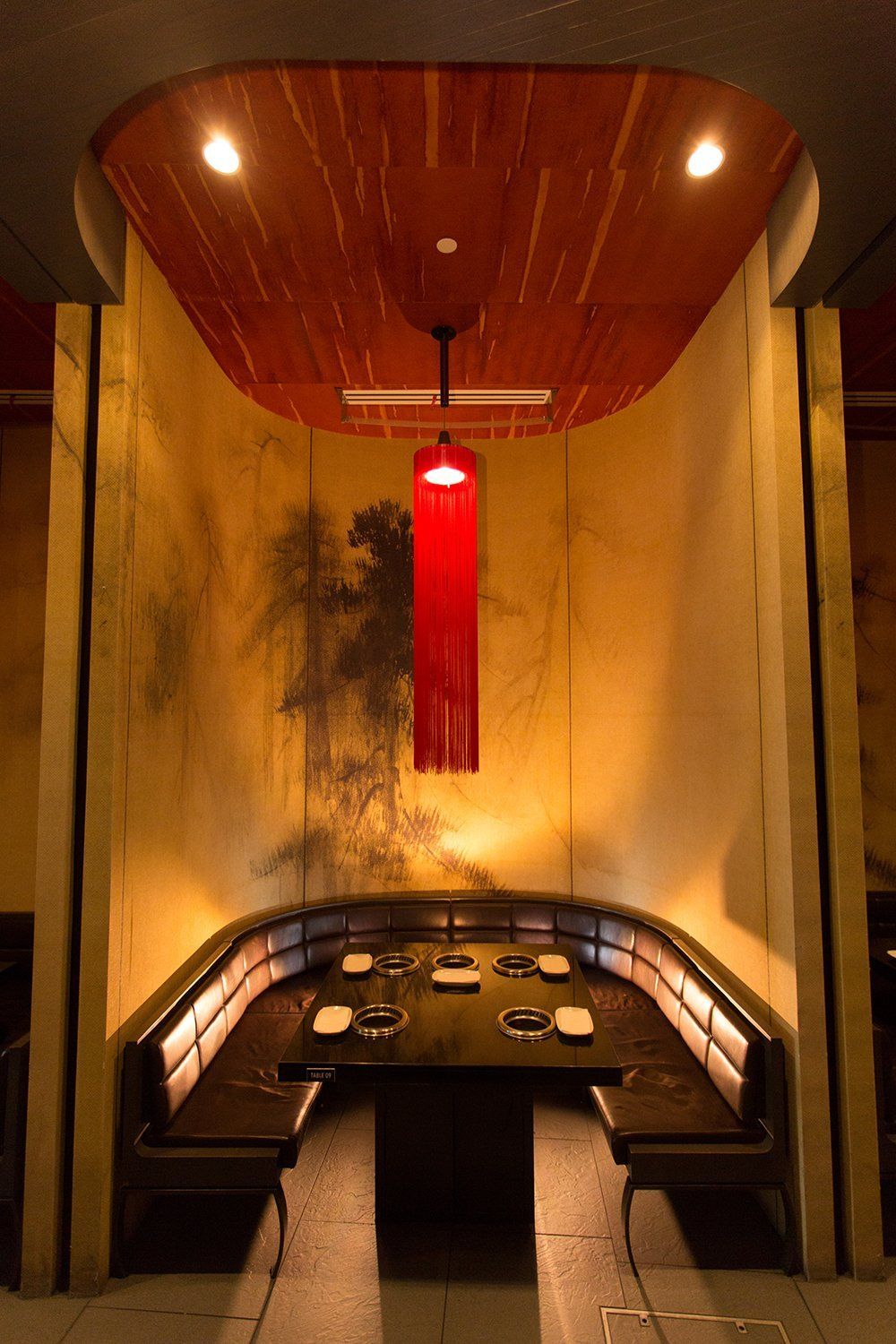 A dining room with a table and benches and a red light hanging from the ceiling.