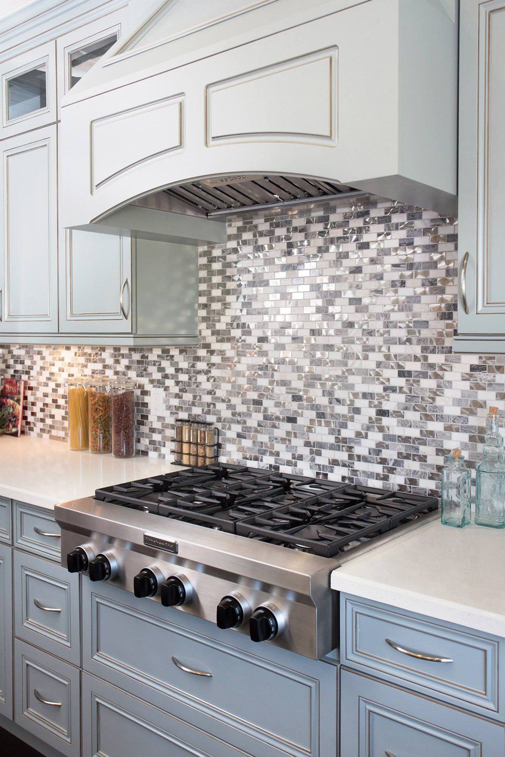 A kitchen with a stove top oven and a hood above it.