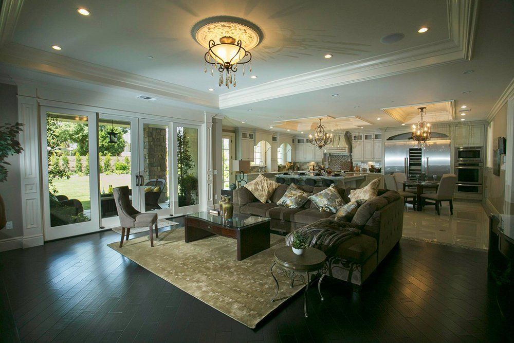 A living room with a couch , chairs , a coffee table and a chandelier.