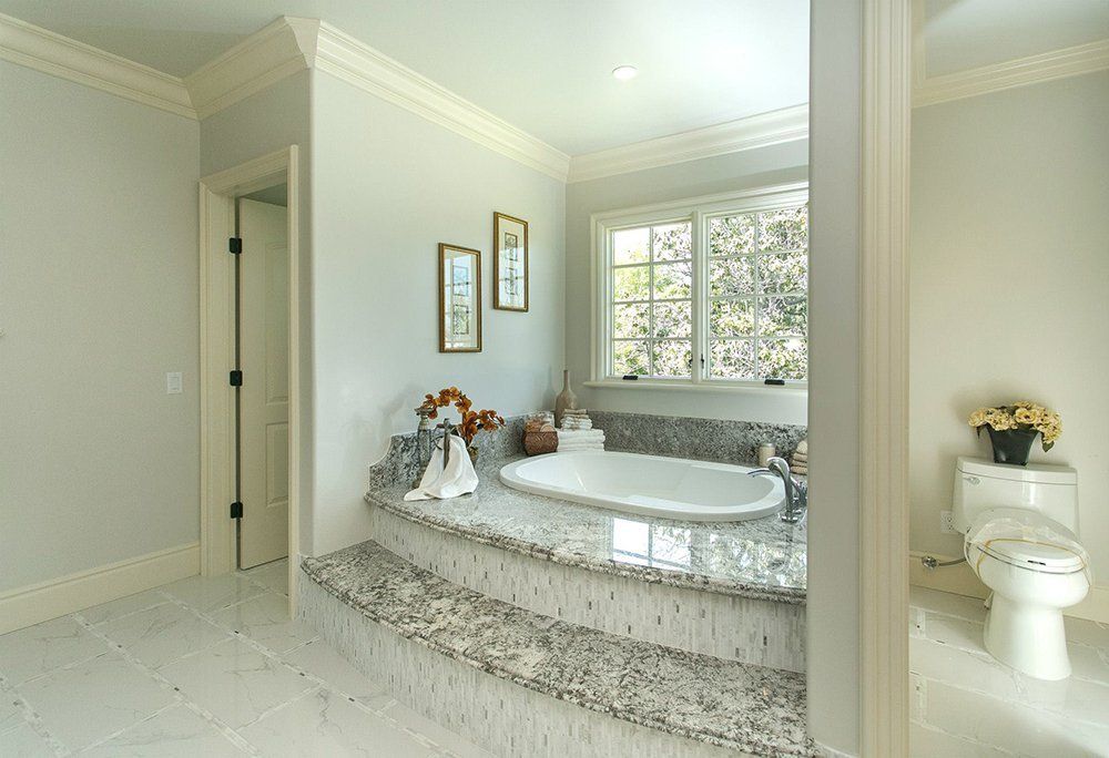 A bathroom with a tub , toilet , and window.