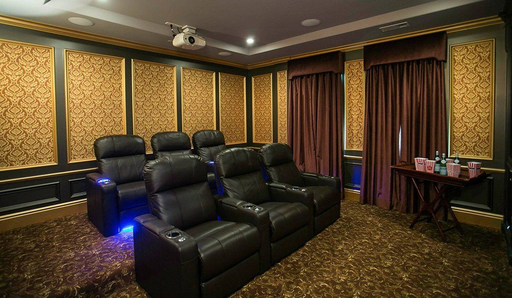 A home theater with black leather chairs and a projector screen.
