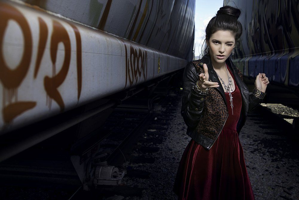 A woman in a red dress is standing next to a train car.