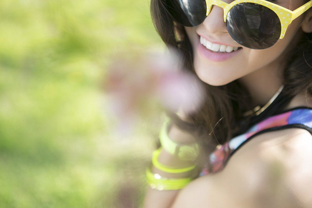 A close up of a woman wearing sunglasses and smiling.