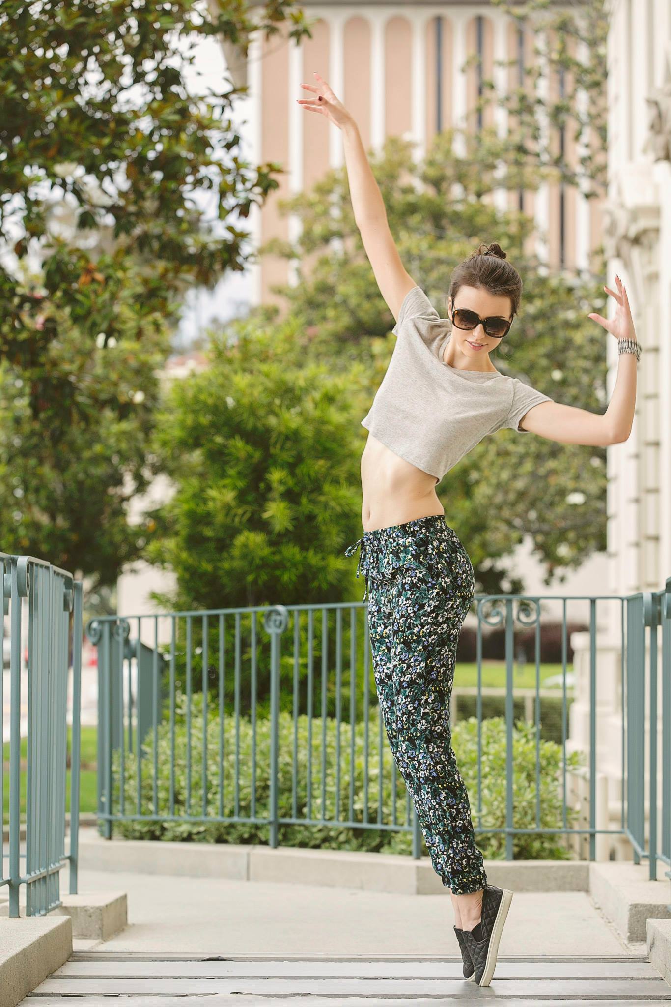 A woman in a crop top and leggings is jumping in the air.