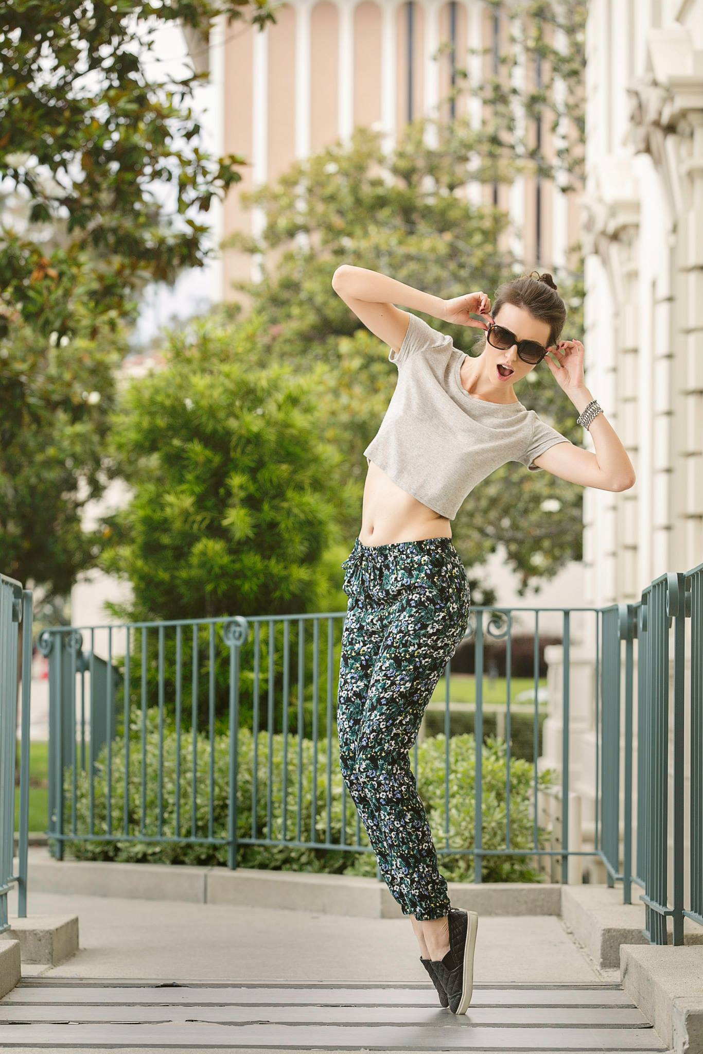 A woman wearing sunglasses and a crop top is jumping in the air.