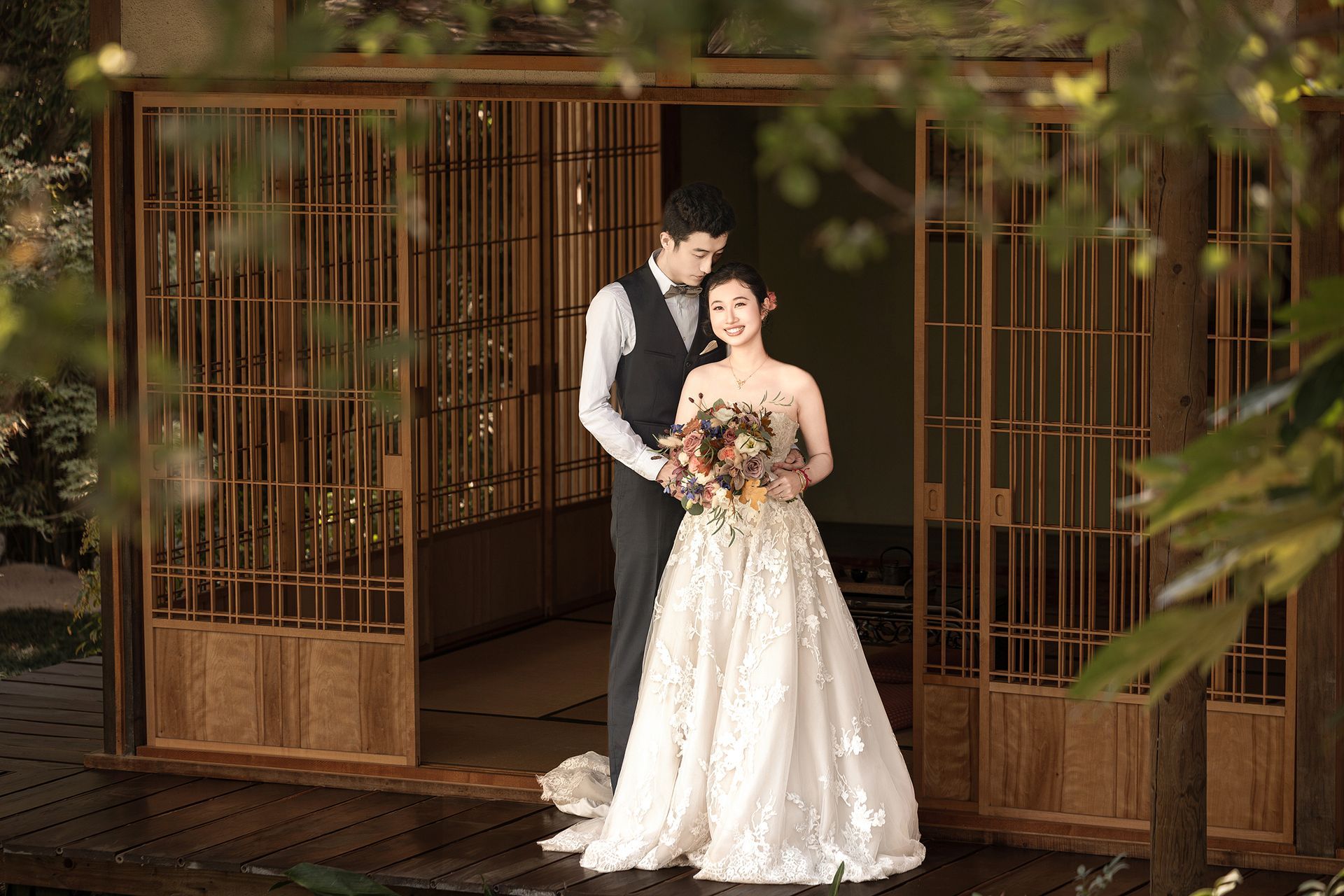 A bride and groom are posing for a picture in front of a wooden building.