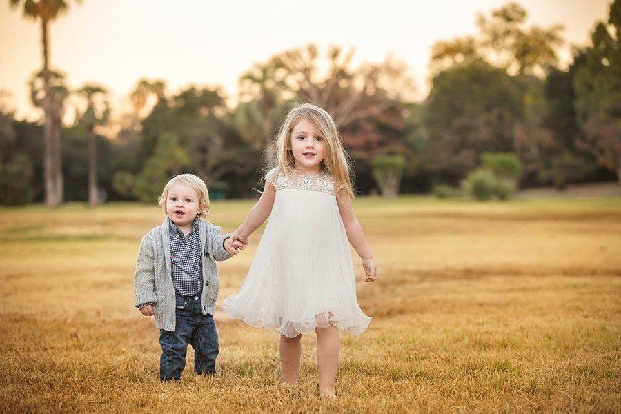 A boy and a girl are holding hands in a field.