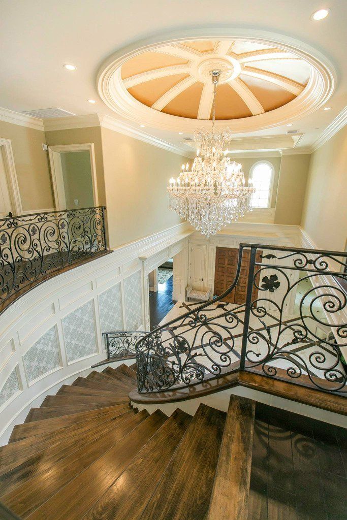 A staircase with a wrought iron railing and a chandelier hanging from the ceiling.