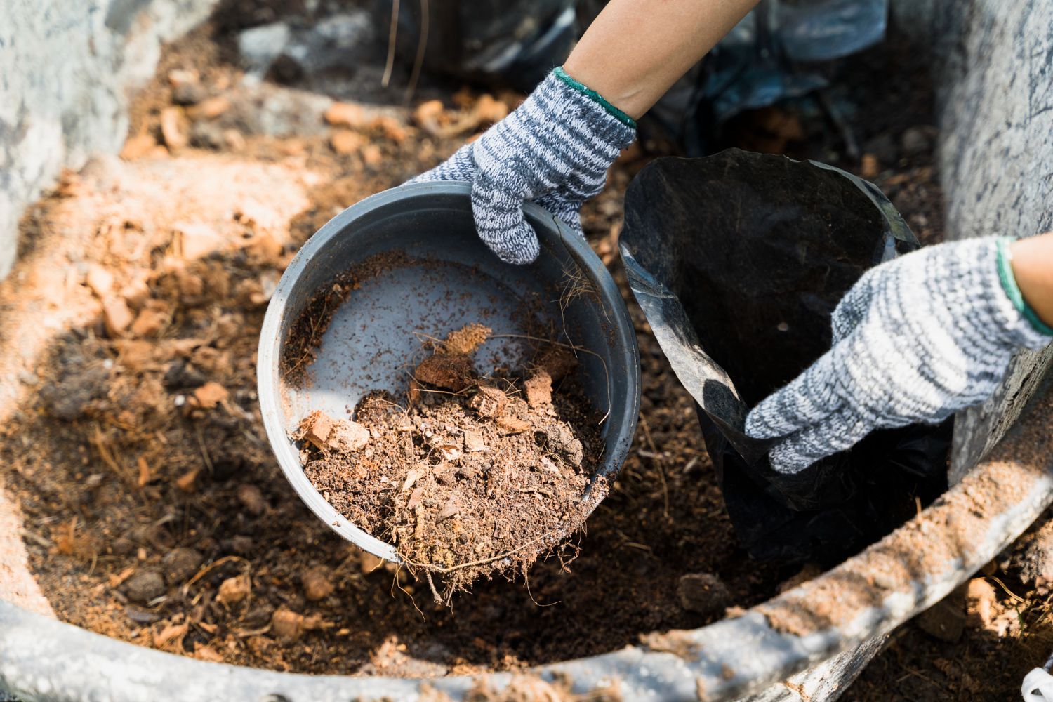 A person is pouring soil into a bucket.