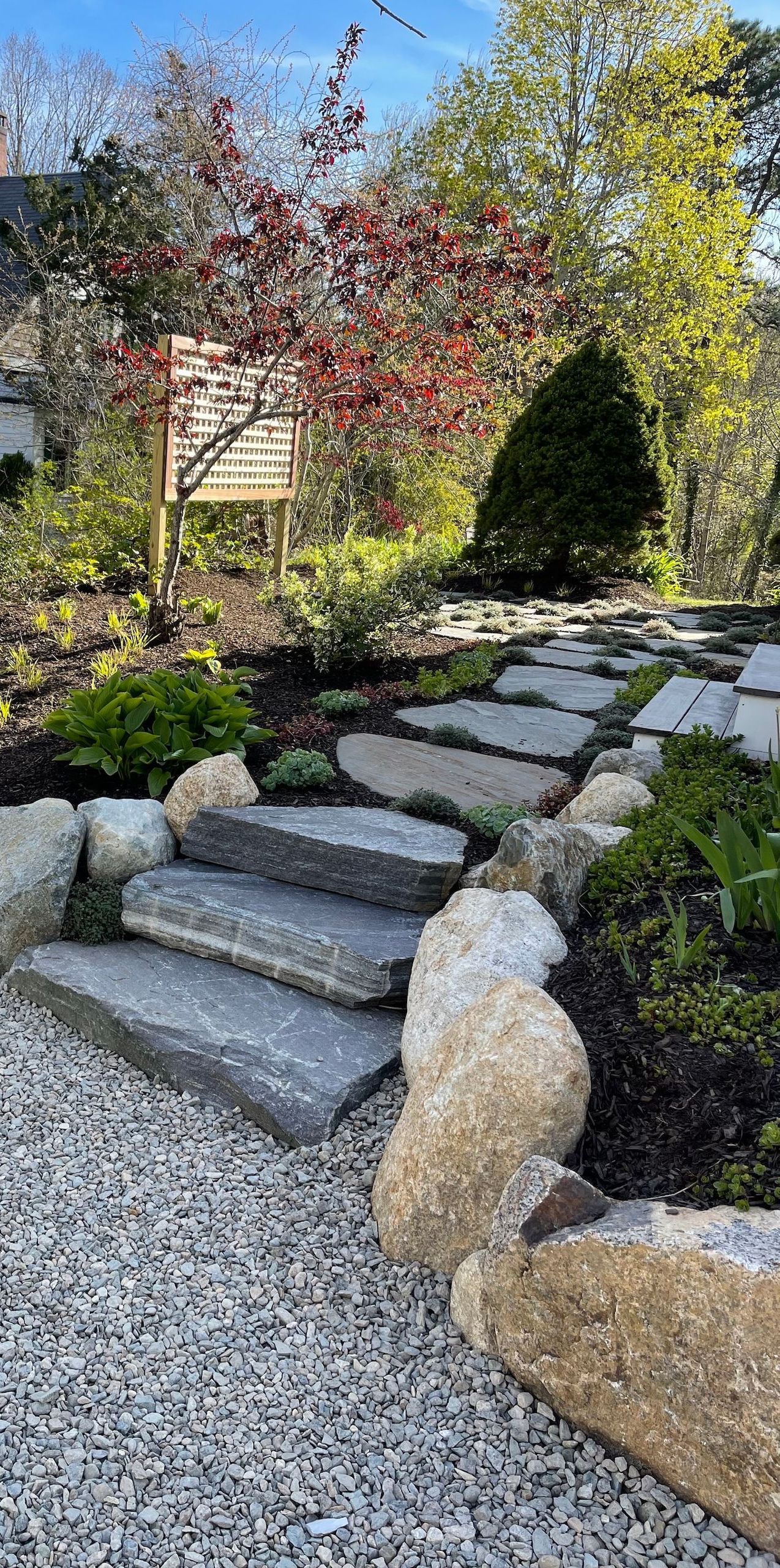 A stone walkway in a garden surrounded by rocks and gravel.