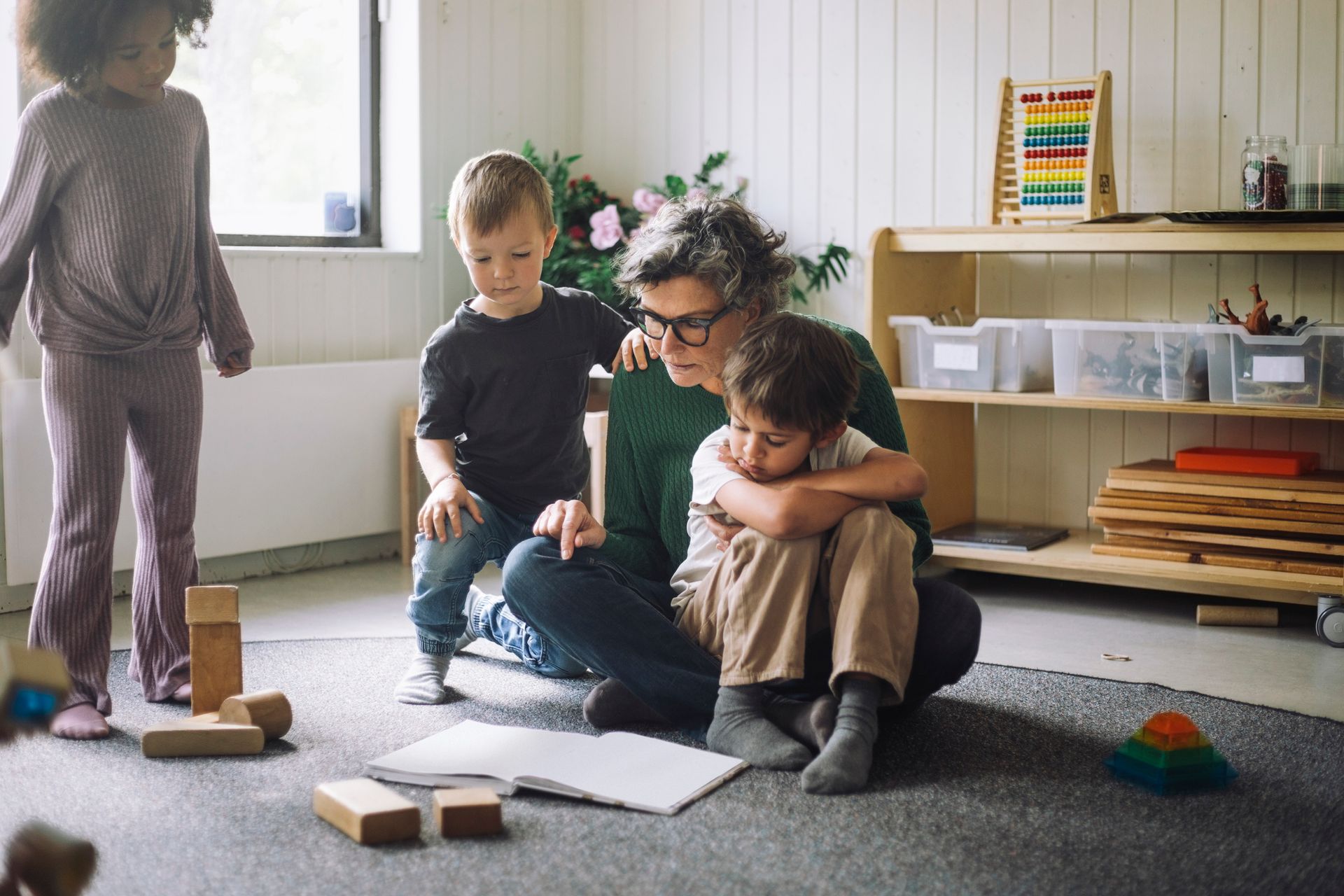 Group of kids sitting with female teacher reading book in childcare centre Group of kids sitting with female teacher reading book in childcare centre